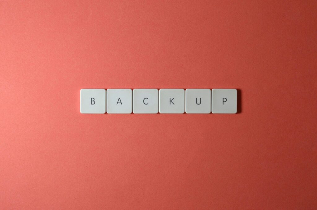 Free Close-up of keyboard keys spelling 'BACKUP' placed on a coral-colored surface. Stock Photo
